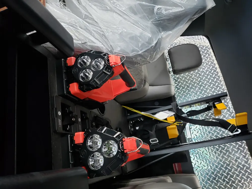 Exterior view of small fire truck showing cab, body compartments, and wheel/tire area.