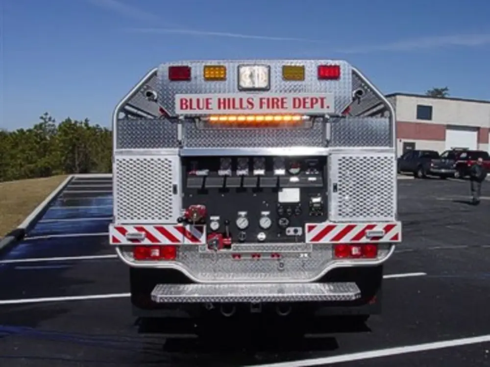 Exterior view of small fire truck showing cab, body compartments, and wheel/tire area.