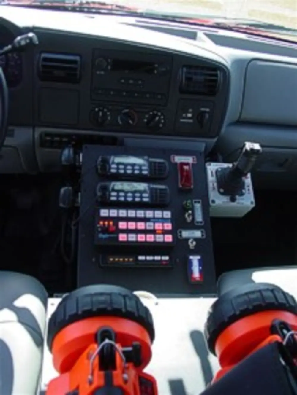 Exterior view of small fire truck showing cab, body compartments, and wheel/tire area.