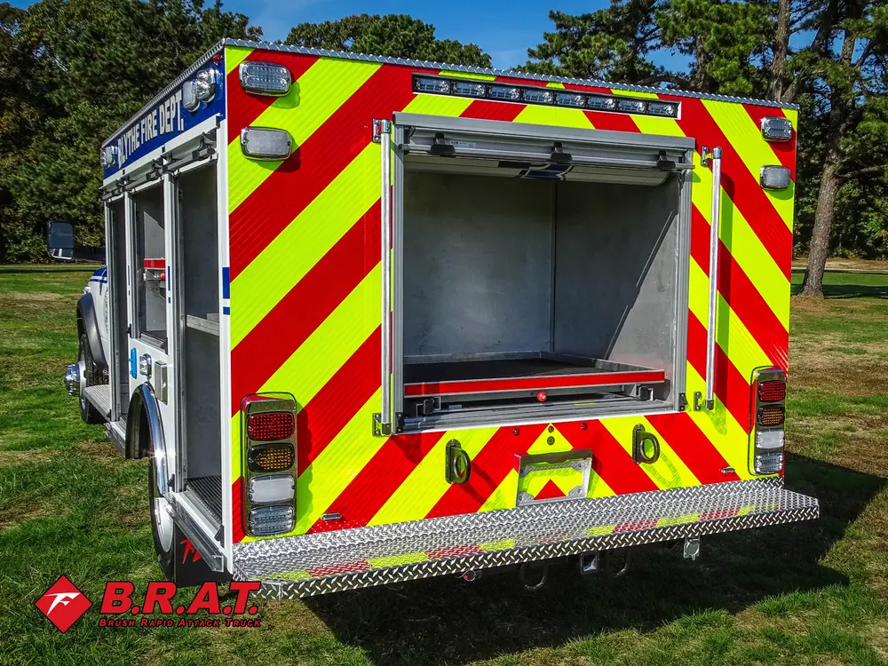 Exterior view of small fire truck showing cab, body compartments, and wheel/tire area.