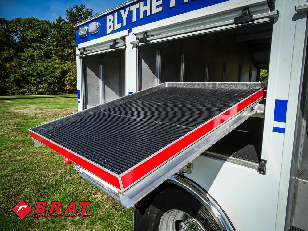 Exterior view of small fire truck showing cab, body compartments, and wheel/tire area.