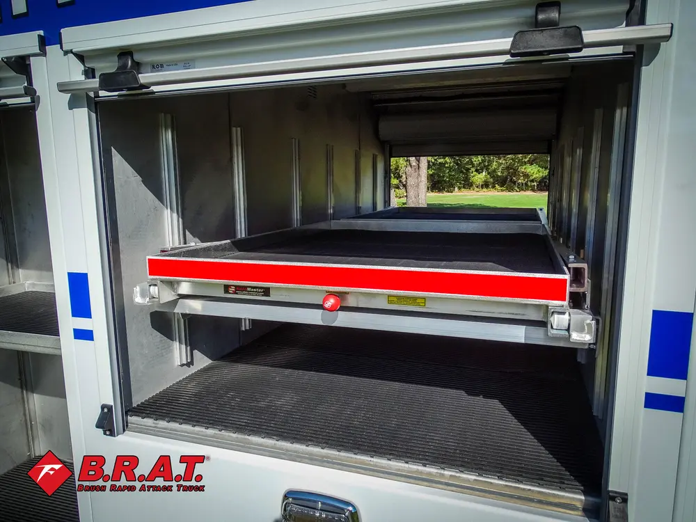 Exterior view of small fire truck showing cab, body compartments, and wheel/tire area.