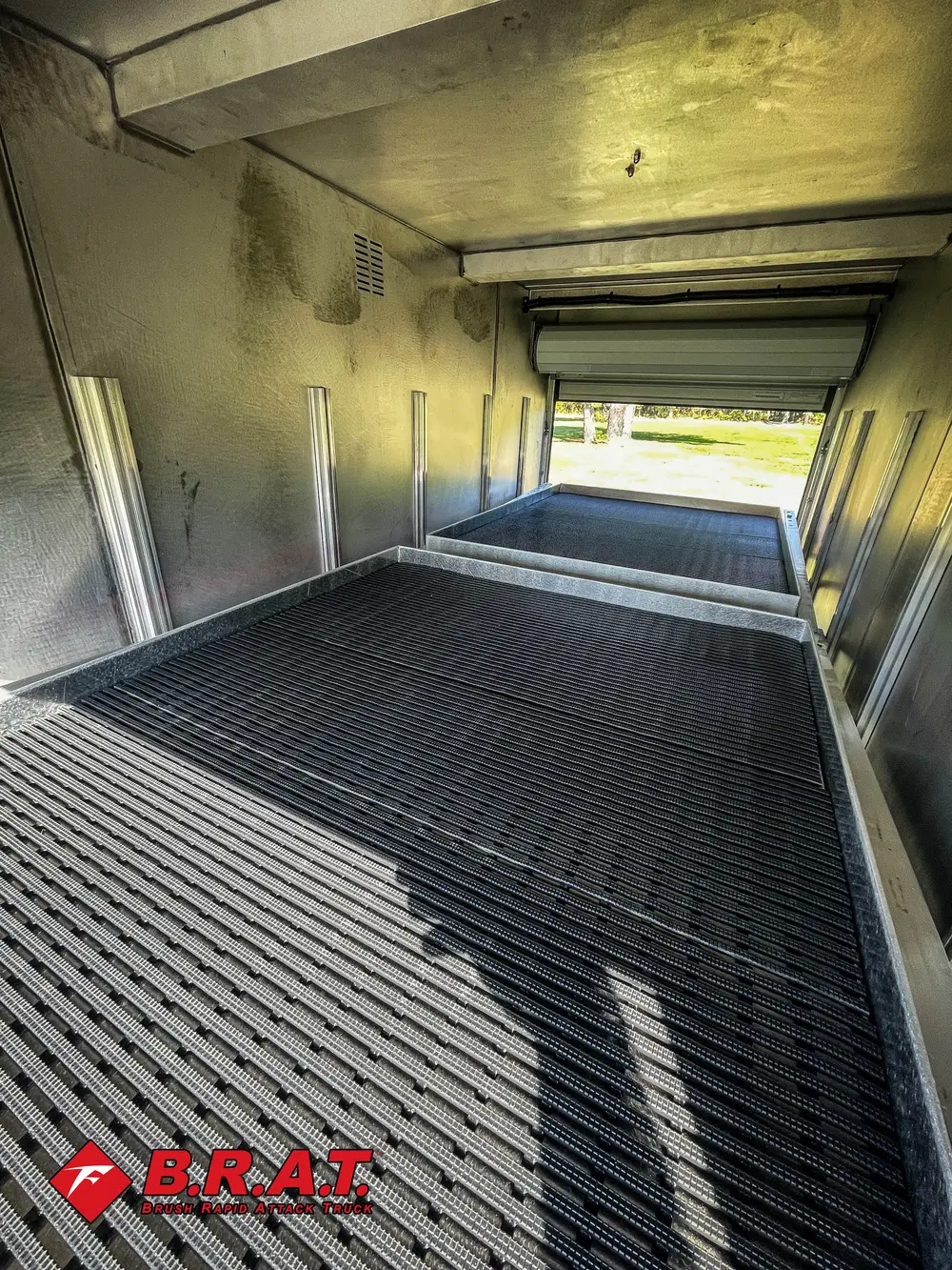 Exterior view of small fire truck showing cab, body compartments, and wheel/tire area.