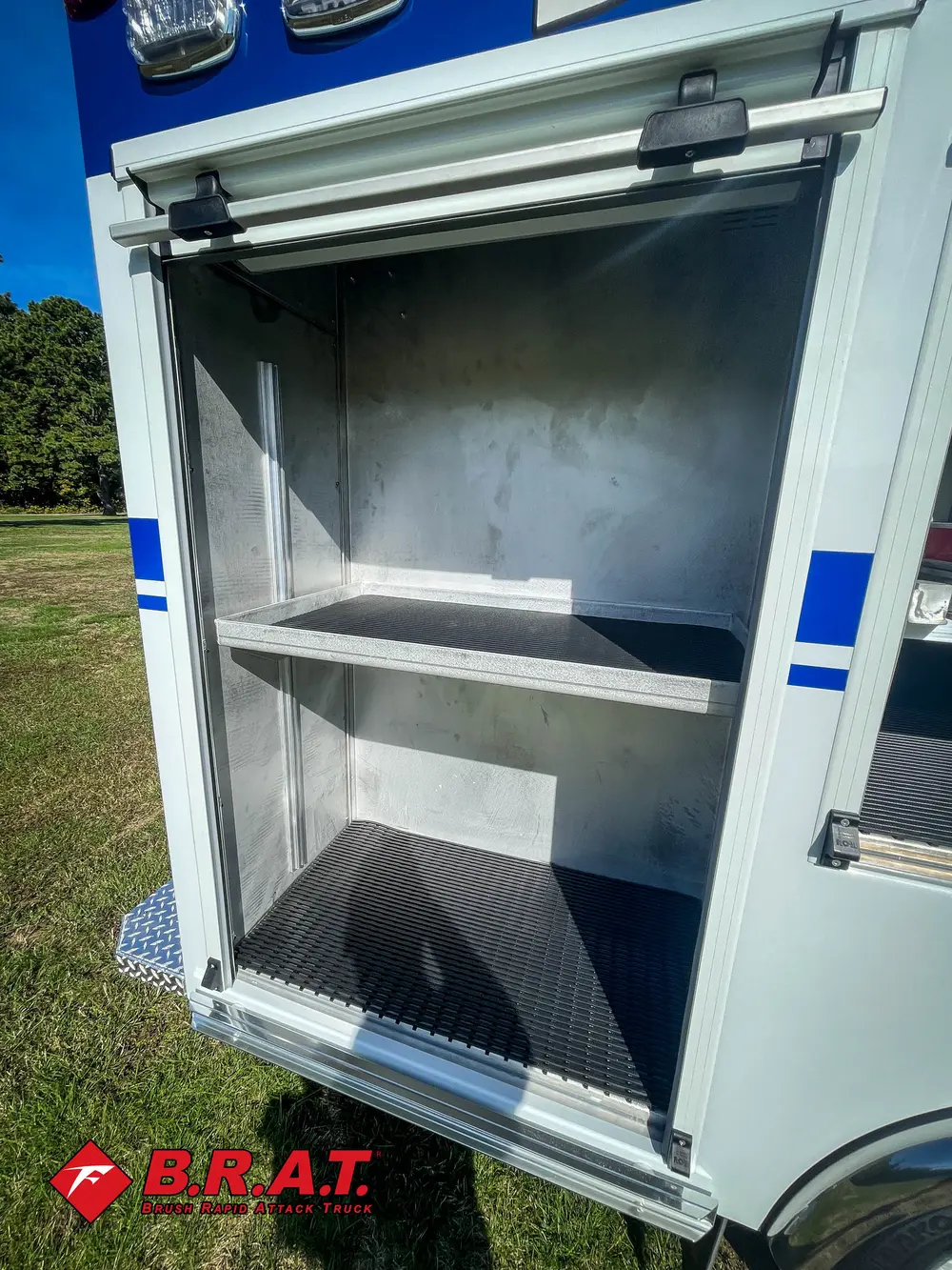 Exterior view of small fire truck showing cab, body compartments, and wheel/tire area.