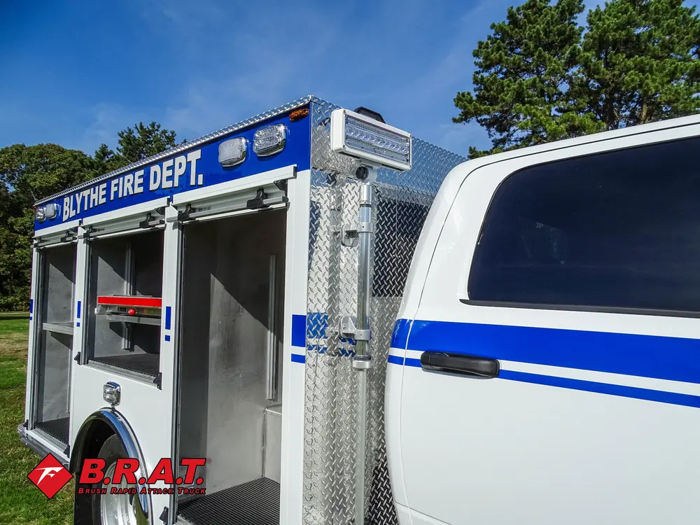 Exterior view of small fire truck showing cab, body compartments, and wheel/tire area.