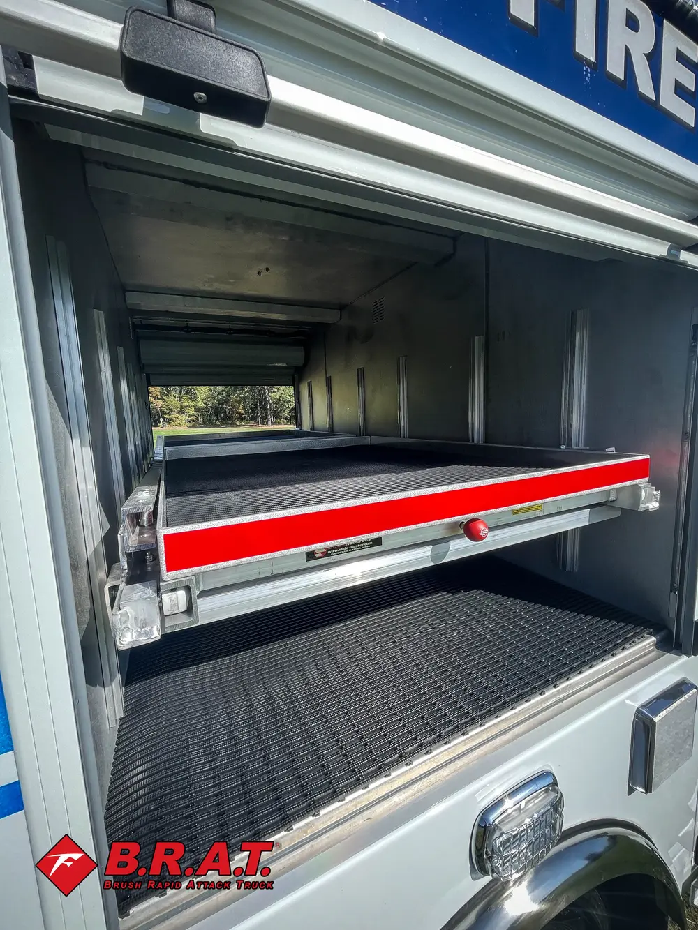 Exterior view of small fire truck showing cab, body compartments, and wheel/tire area.