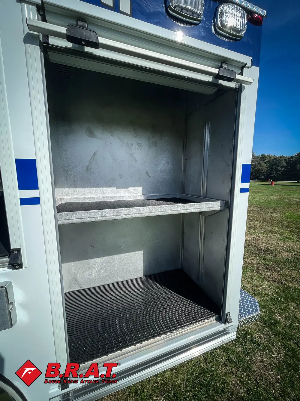 Exterior view of small fire truck showing cab, body compartments, and wheel/tire area.