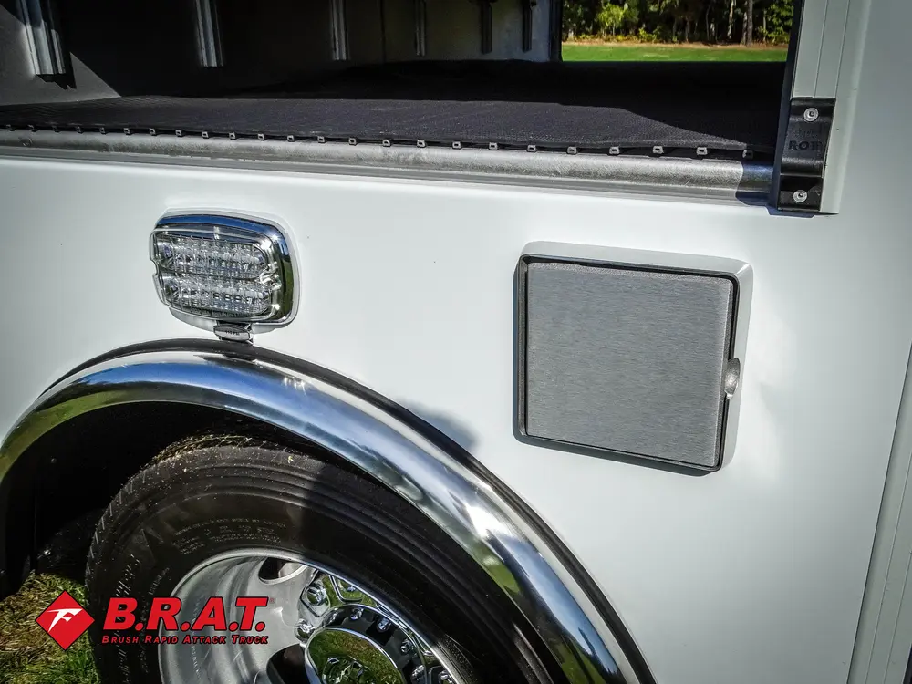 Exterior view of small fire truck showing cab, body compartments, and wheel/tire area.