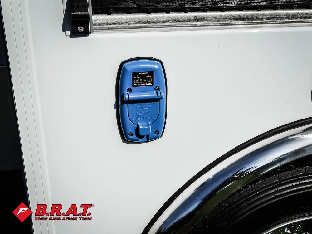 Exterior view of small fire truck showing cab, body compartments, and wheel/tire area.