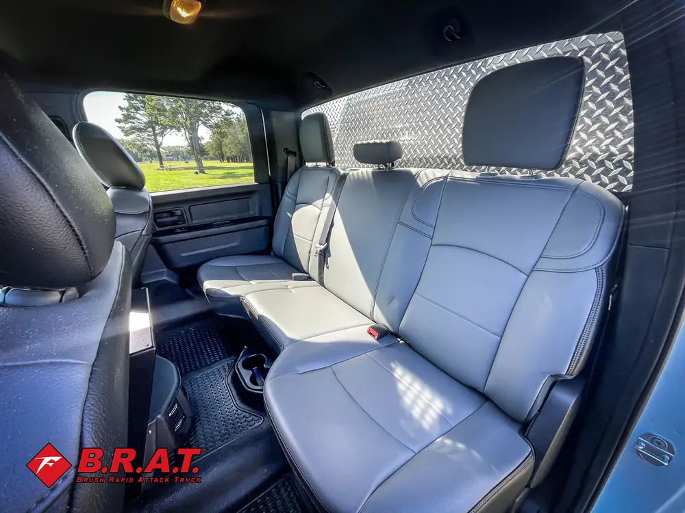 Exterior view of small fire truck showing cab, body compartments, and wheel/tire area.