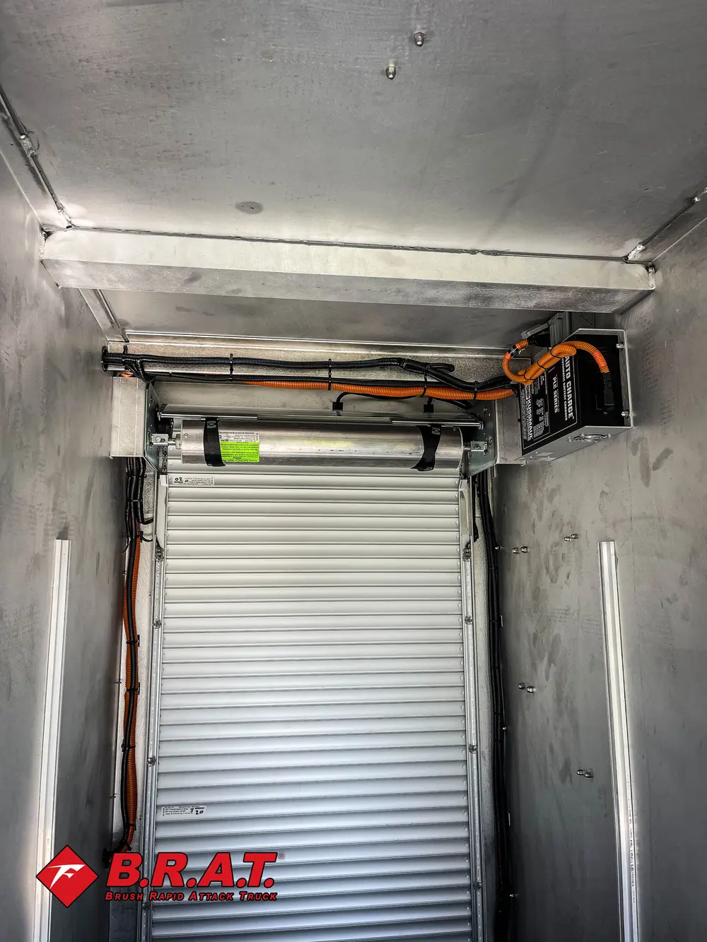 Exterior view of small fire truck showing cab, body compartments, and wheel/tire area.