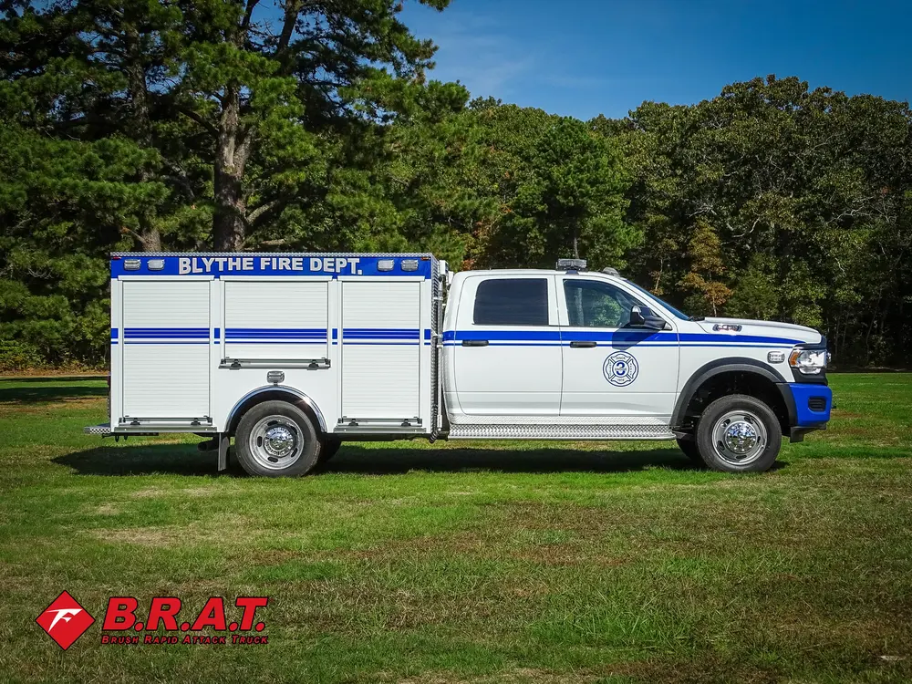 Exterior view of small fire truck showing cab, body compartments, and wheel/tire area.