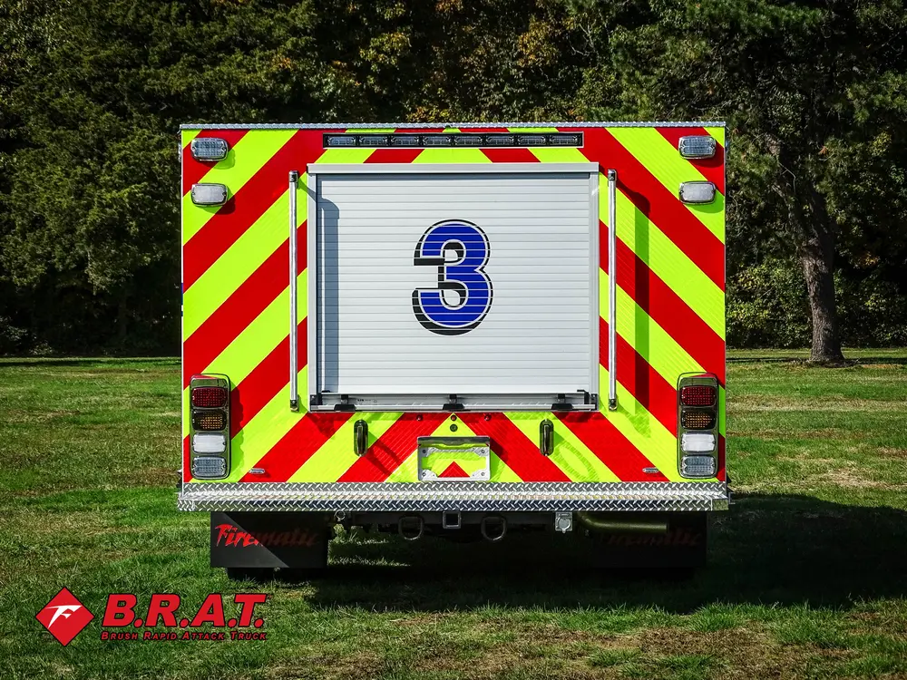Exterior view of small fire truck showing cab, body compartments, and wheel/tire area.