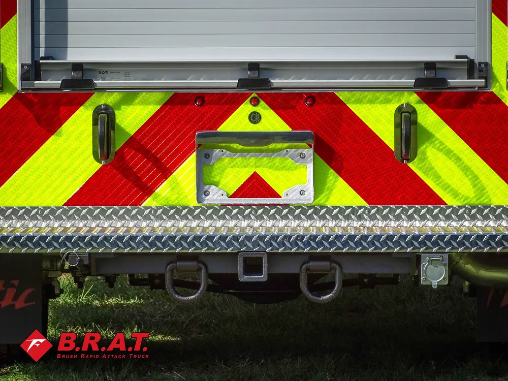 Exterior view of small fire truck showing cab, body compartments, and wheel/tire area.