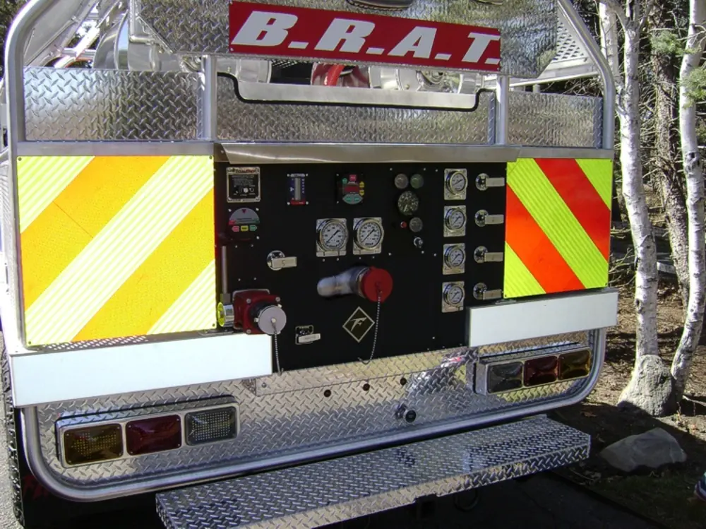 Exterior view of small fire truck showing cab, body compartments, and wheel/tire area.