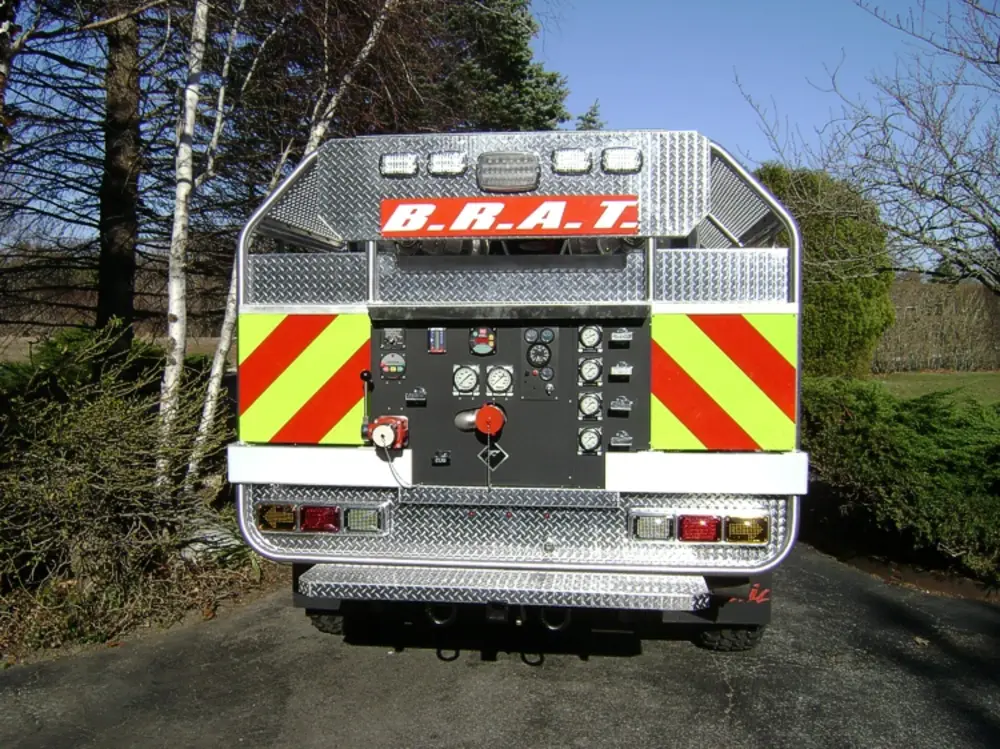 Exterior view of small fire truck showing cab, body compartments, and wheel/tire area.