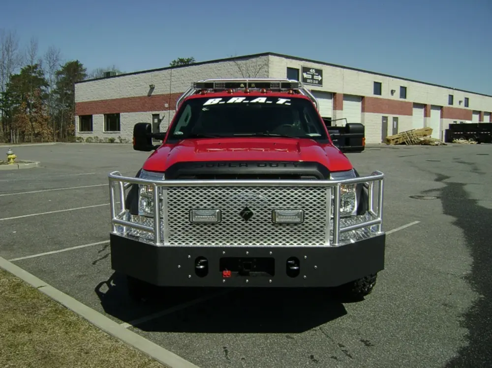 Exterior view of small fire truck showing cab, body compartments, and wheel/tire area.