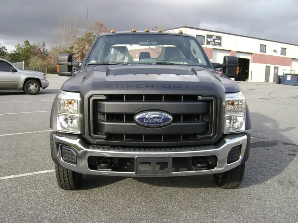 Exterior view of small fire truck showing cab, body compartments, and wheel/tire area.