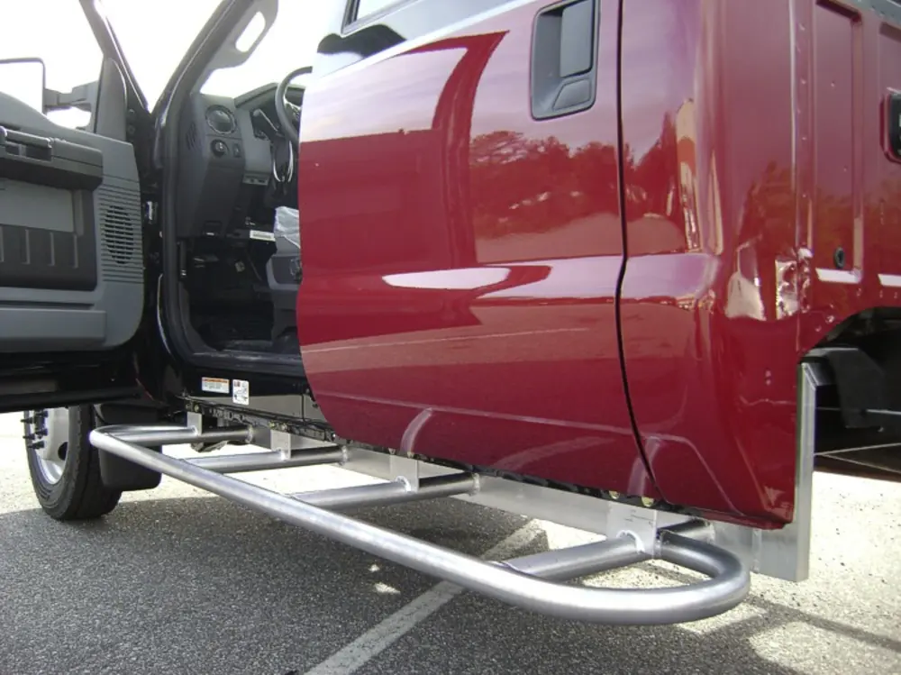 Exterior view of small fire truck showing cab, body compartments, and wheel/tire area.