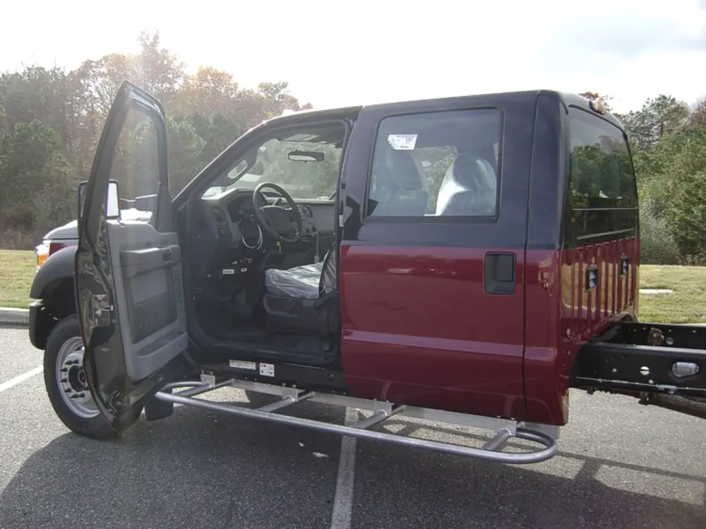 Exterior view of small fire truck showing cab, body compartments, and wheel/tire area.