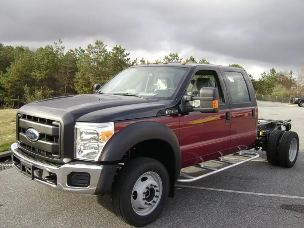 Exterior view of small fire truck showing cab, body compartments, and wheel/tire area.