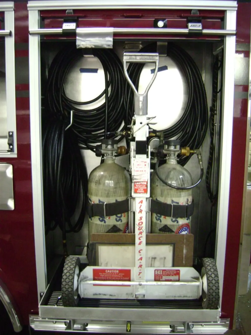 Exterior view of small fire truck showing cab, body compartments, and wheel/tire area.