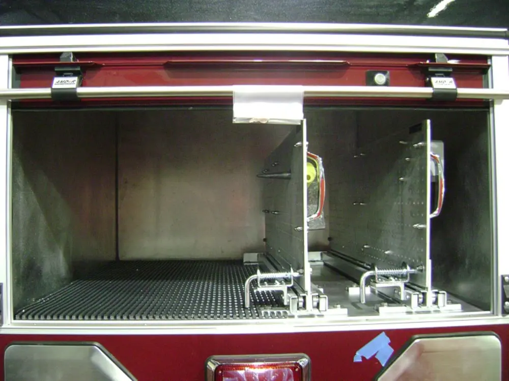 Exterior view of small fire truck showing cab, body compartments, and wheel/tire area.