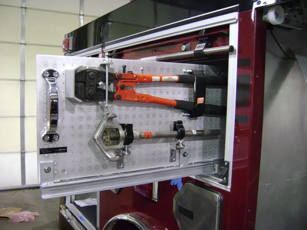 Exterior view of small fire truck showing cab, body compartments, and wheel/tire area.