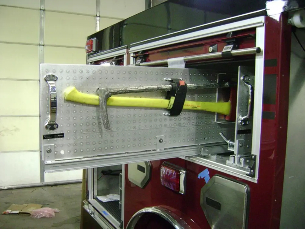 Exterior view of small fire truck showing cab, body compartments, and wheel/tire area.