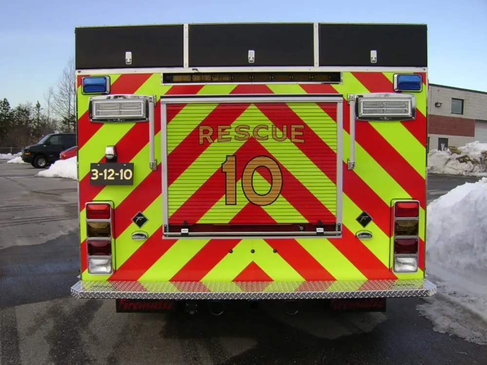 Exterior view of small fire truck showing cab, body compartments, and wheel/tire area.