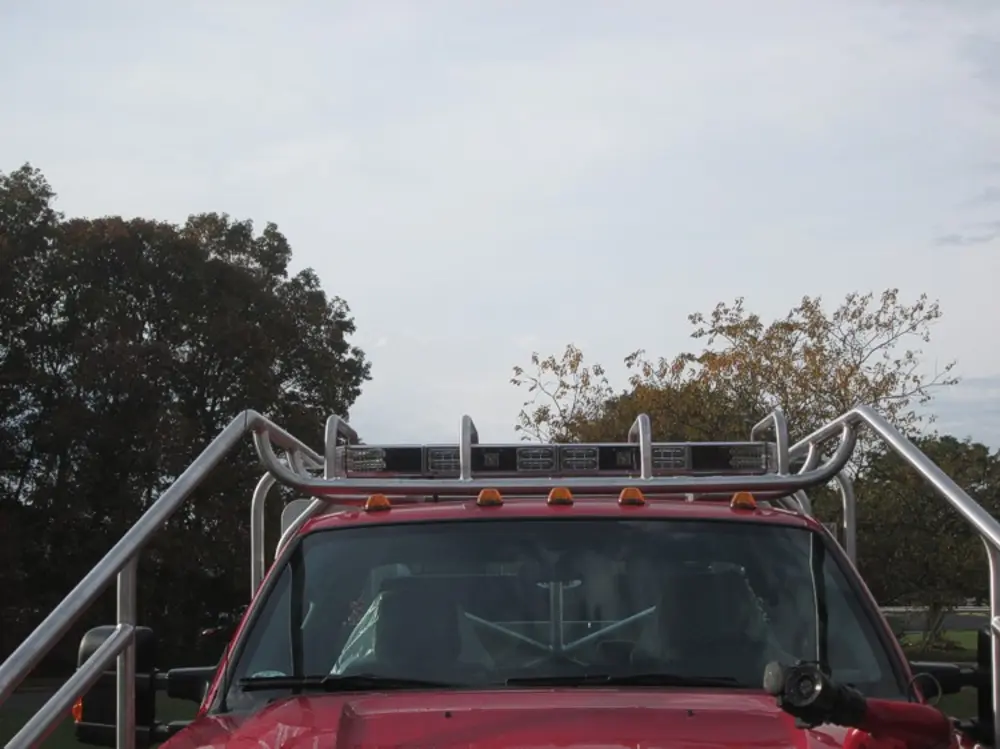 Exterior view of small fire truck showing cab, body compartments, and wheel/tire area.