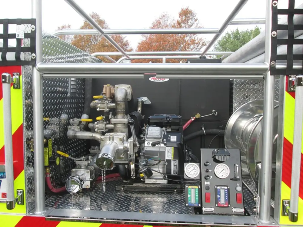 Exterior view of small fire truck showing cab, body compartments, and wheel/tire area.