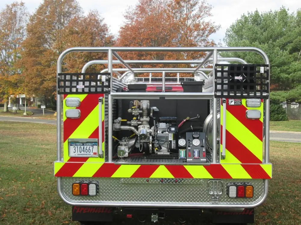 Exterior view of small fire truck showing cab, body compartments, and wheel/tire area.