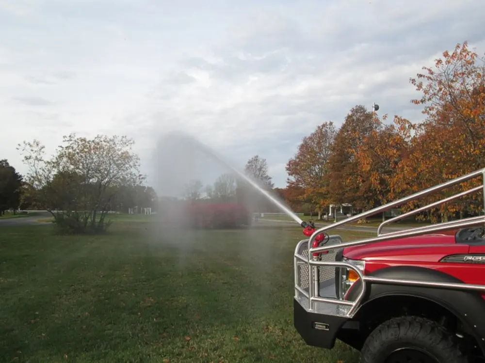 Exterior view of small fire truck showing cab, body compartments, and wheel/tire area.
