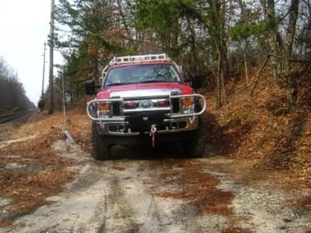 Exterior view of small fire truck showing cab, body compartments, and wheel/tire area.
