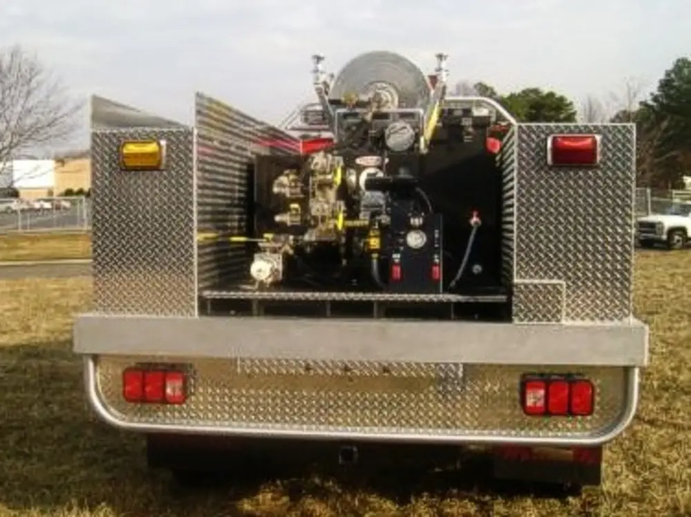 Exterior view of small fire truck showing cab, body compartments, and wheel/tire area.