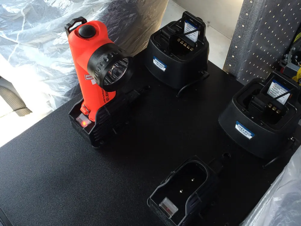 Exterior view of small fire truck showing cab, body compartments, and wheel/tire area.