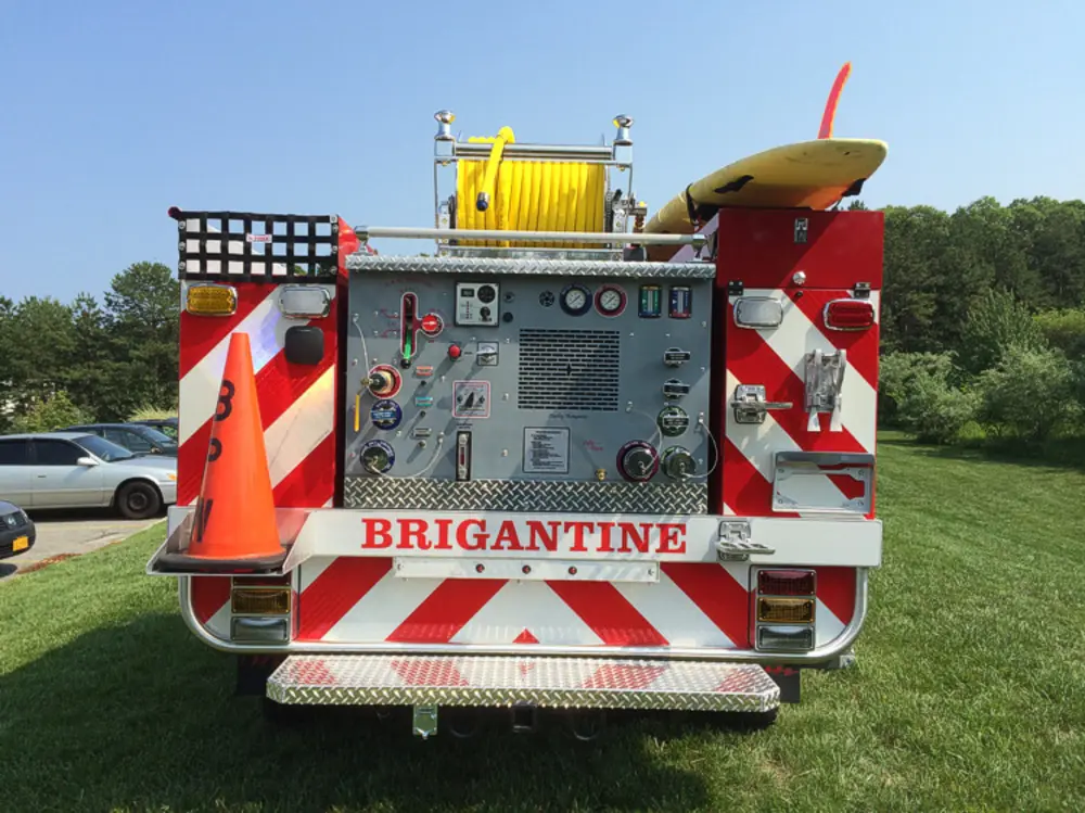 Exterior view of small fire truck showing cab, body compartments, and wheel/tire area.