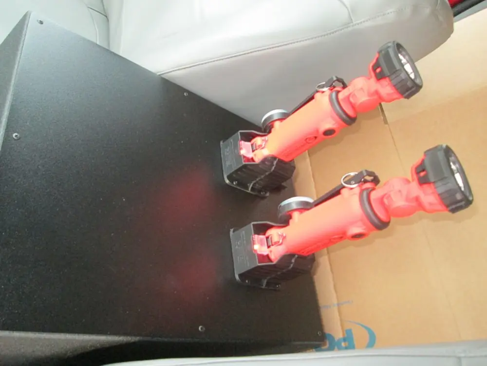 Exterior view of small fire truck showing cab, body compartments, and wheel/tire area.