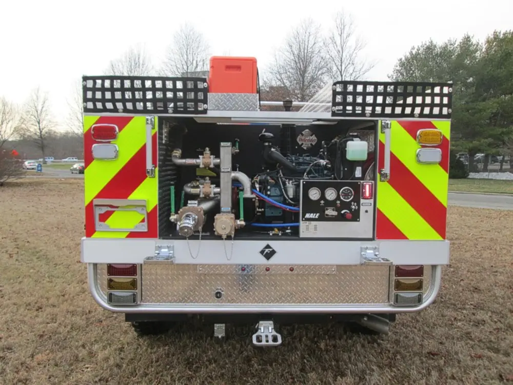 Exterior view of small fire truck showing cab, body compartments, and wheel/tire area.