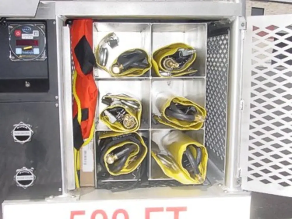 Exterior view of small fire truck showing cab, body compartments, and wheel/tire area.