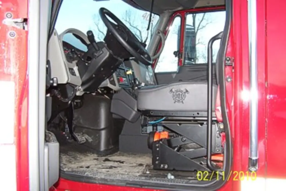 Exterior view of small fire truck showing cab, body compartments, and wheel/tire area.