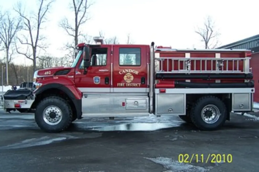 Exterior view of small fire truck showing cab, body compartments, and wheel/tire area.
