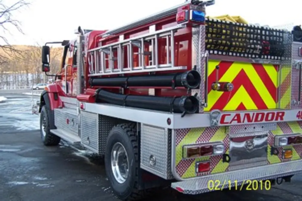 Exterior view of small fire truck showing cab, body compartments, and wheel/tire area.