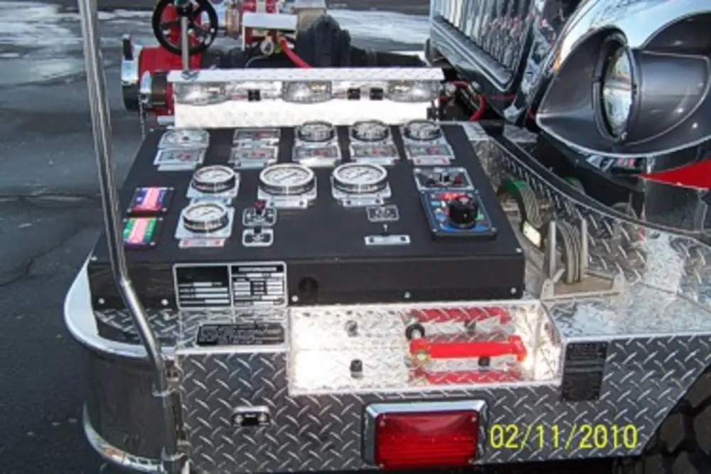 Exterior view of small fire truck showing cab, body compartments, and wheel/tire area.