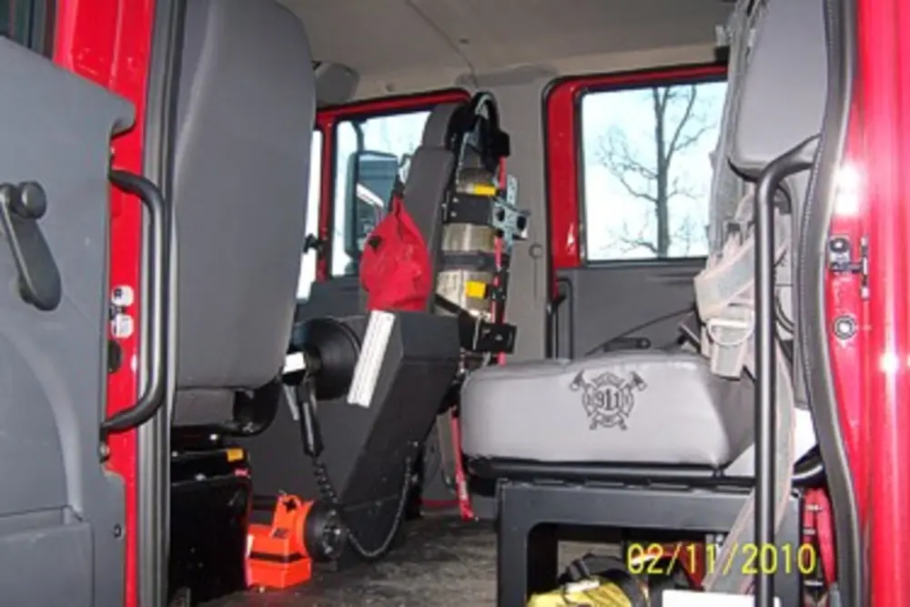Exterior view of small fire truck showing cab, body compartments, and wheel/tire area.
