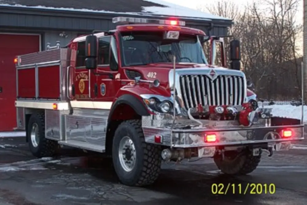Exterior view of small fire truck showing cab, body compartments, and wheel/tire area.