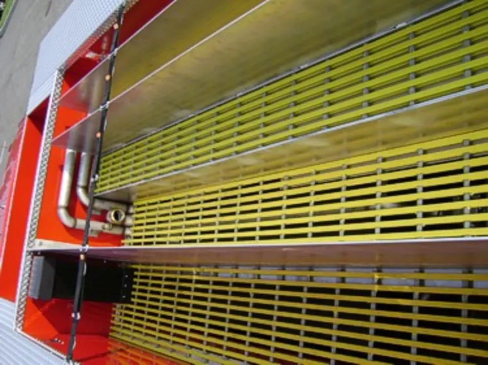 Exterior view of small fire truck showing cab, body compartments, and wheel/tire area.