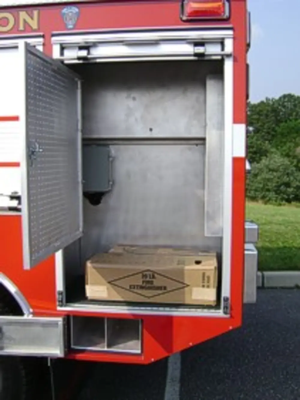 Exterior view of small fire truck showing cab, body compartments, and wheel/tire area.