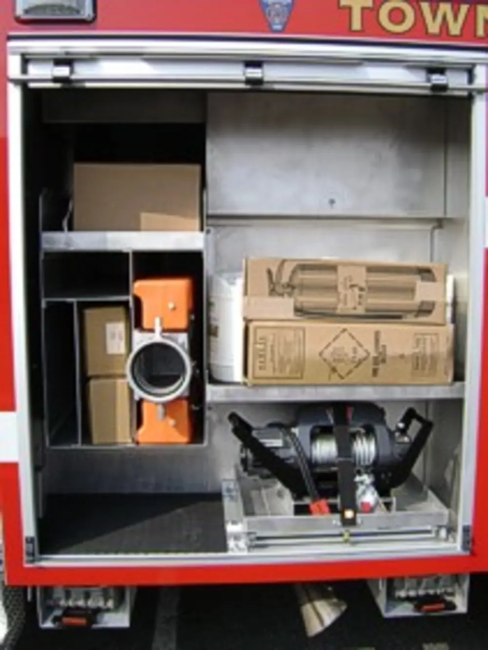 Exterior view of small fire truck showing cab, body compartments, and wheel/tire area.